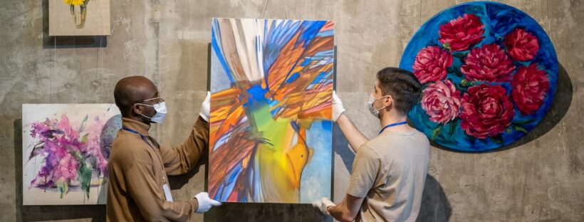 People hanging paintings for exhibition