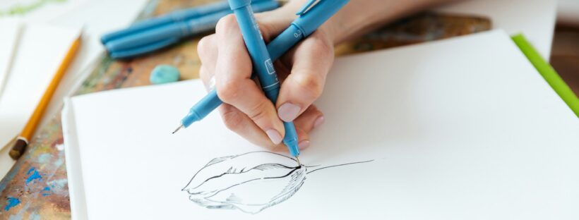 Woman artist hands drawing with gel ink pen in sketchbook